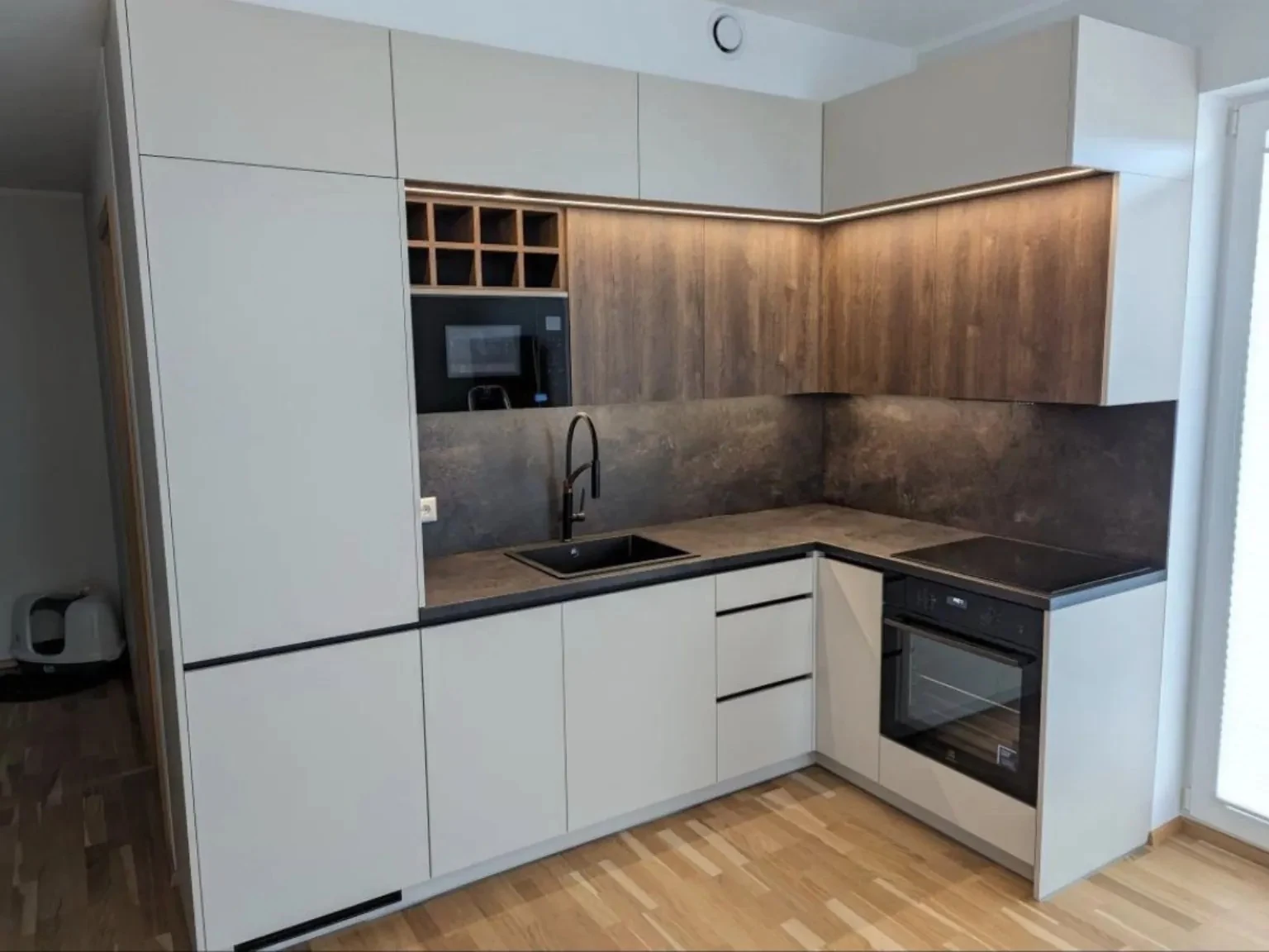 Completed compact kitchen with white tall units, timber-effect wall cabinets and dark worktops in Dublin
