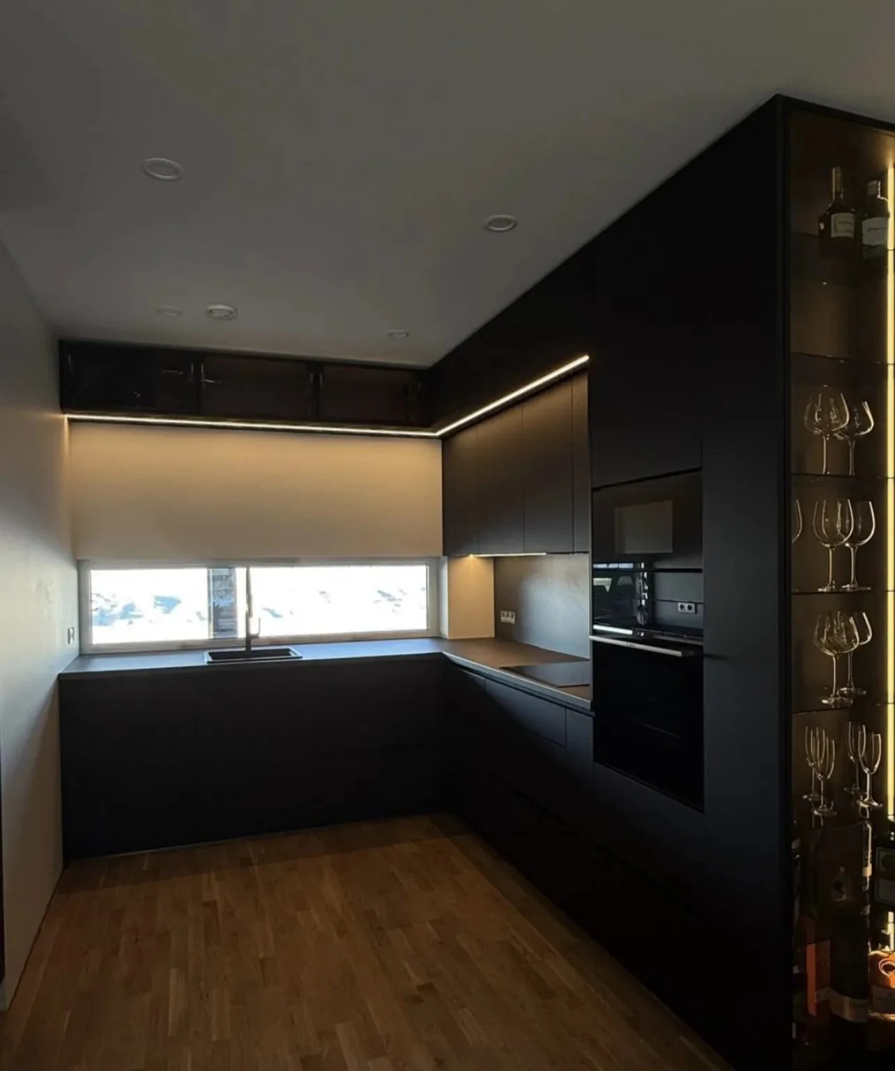 Completed dark kitchen with integrated appliances, concealed lighting and illuminated glass display storage in Dublin
